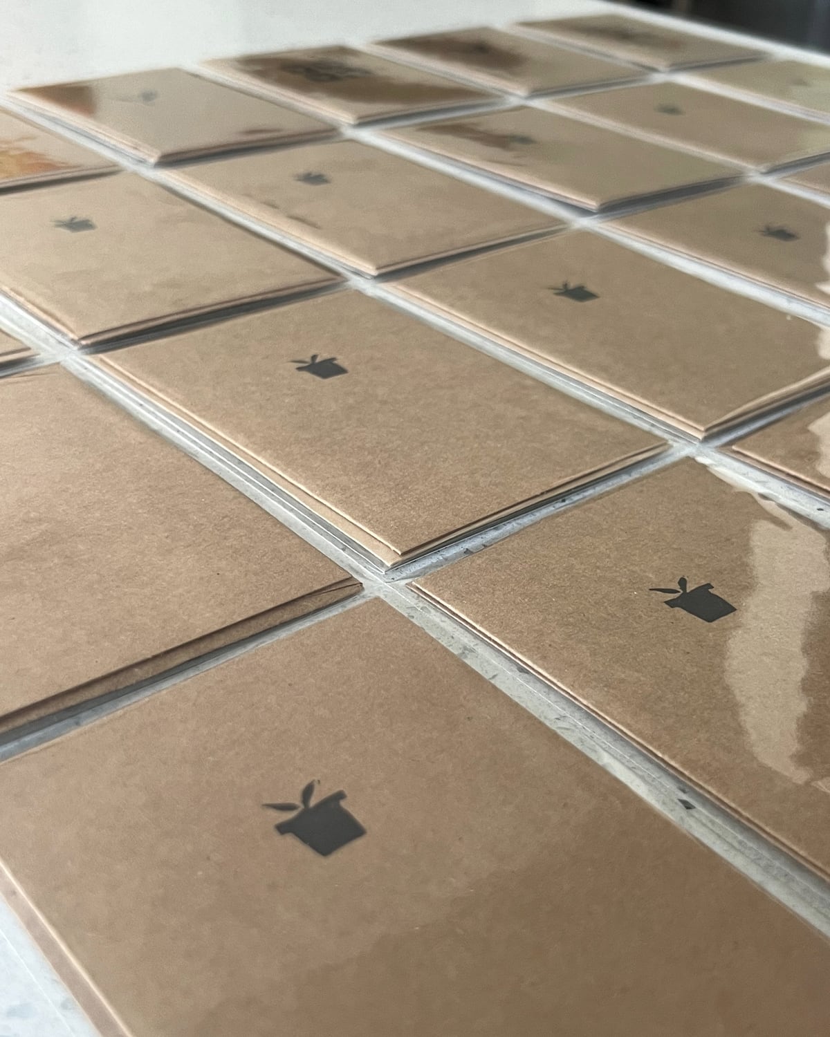 Hand-stamped kraft cards laid out in rows, each pressed by hand with a small motif.